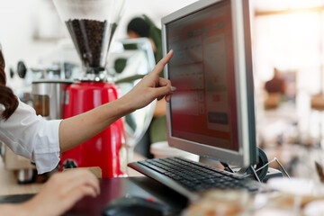 Barista hand pointing touchscreen computer at a coffee shop, processing customer orders and managing sales