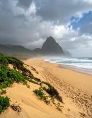 Sandy beach meets dramatic mountain under stormy sky