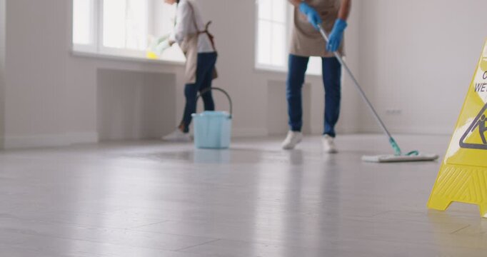 Janitorial team cleaning service industry, professional people washing floor, window sill, cleaning building, office space, mopping, housekeeping job, yellow caution wet floor board standing