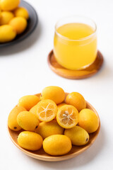 Fresh kumquats fruit and juice on white background