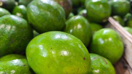 Fresh green avocados stacked together in a market display. Close-up texture highlights natural ripeness and organic produce, perfect for themes of healthy food, nutrition, and freshness.