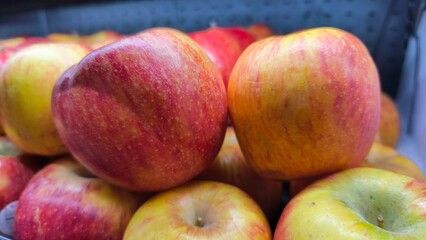Fresh red apples stacked on a market display. Close-up shot highlighting the vibrant color, natural texture, and freshness, perfect for concepts of healthy eating, organic produce, and nutrition.
