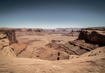 Fototapeta premium Vast arid desert landscape with deep canyons and towering mesas under a clear sky