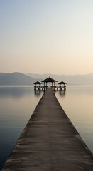 Fototapeta premium Serene Pier extending into tranquil water with gazebo under a clear sky