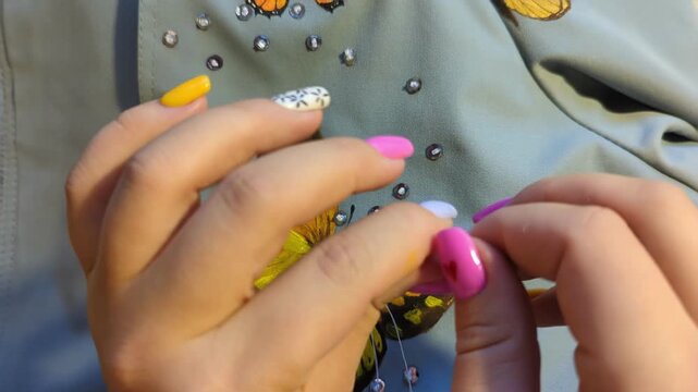 Crafting process of attaching a butterfly patch to fabric with decorative beads and stitches, showcasing creative textile art. Handmade process, handwork.