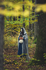 Horror background of a ghostly figure in enchanted a forest on a moody autumn day.