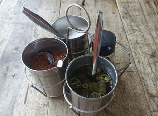 Spice caddy metal containers jalapeno chili flakes vinegar spoon rustic table condiment set add lively flavor