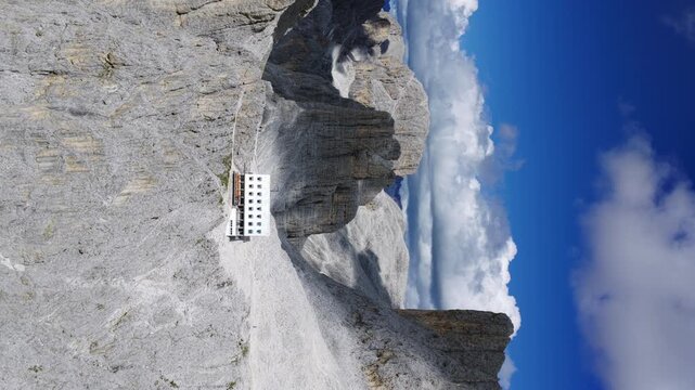Re Alberto mountain hut nestled at base of dramatic Vajolet Towers, Dolomites, Italy. Aerial drone lateral view, vertical format
