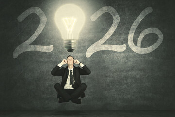 Businessman Meditating or Concentrating Under a Bright Light Bulb Idea for the Year 2026 Strategy