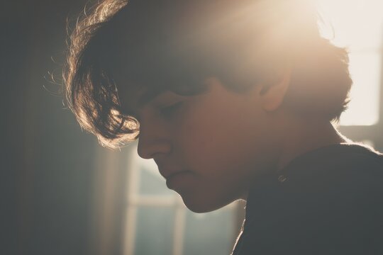 Pensive Teenager in Soft Sunlight Profile View Indoors Contemplative Mood Natural Light Portrait