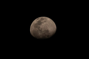 Obraz premium Imagen astronómica de la Luna en fase gibosa creciente, mostrando detalles de su superficie, cráteres y mares lunares sobre un fondo negro. 