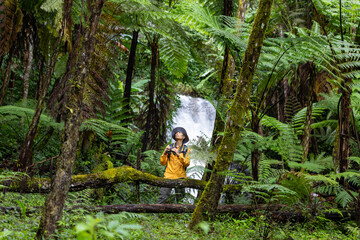 Asian naturalist bird watching is holding the binoculars while exploring in the tree fern forest for surveying and discovering the rare biodiversity species and ecologist on the field study