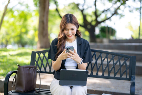 Young woman smiling using smartphone and tablet outdoors