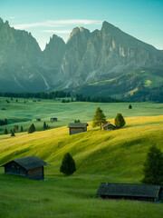 Beautiful sunrise with fields, cottages and mountains. Alpe di Siusi, Dolomites, Italy