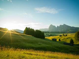 Beautiful sunrise with fields, cottages and mountains. Alpe di Siusi, Dolomites, Italy