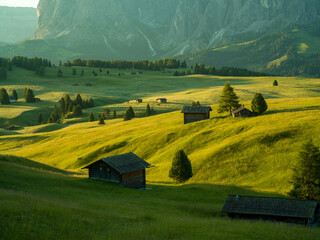 Beautiful sunrise with fields, cottages and mountains. Alpe di Siusi, Dolomites, Italy