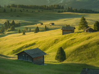 Beautiful sunrise with fields, cottages and mountains. Alpe di Siusi, Dolomites, Italy