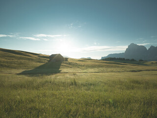Beautiful sunrise with fields, cottages and mountains. Alpe di Siusi, Dolomites, Italy