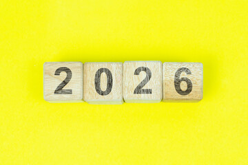 Number 2026 on wooden cubes. New Year concept. Isolated on yellow background