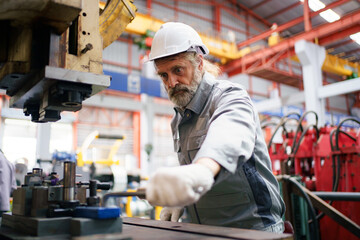 Skilled worker operating metal sheet machine in factory.