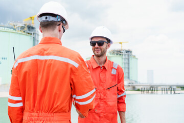 Refinery engineers shaking hands after project success at oil plant.