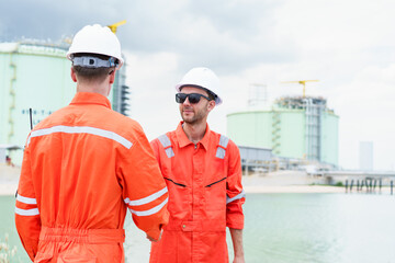 Refinery engineers shaking hands after project success at oil plant.