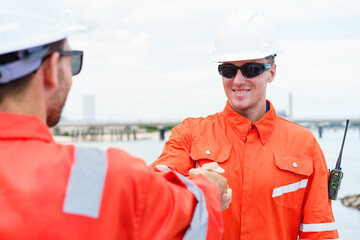 Refinery engineers shaking hands after project success at oil plant.