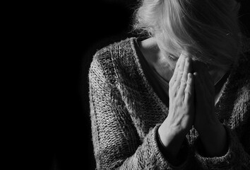 woman praying with hands together on grey black background with people stock image stock photo