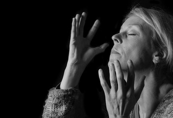woman praying with hands together on grey black background with people stock image stock photo