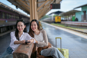 Fototapeta premium Two women sitting on a bench at a train station