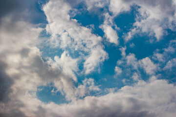 Fluffy, vibrant cumulus clouds float across a bright blue expanse. A serene, airy atmosphere fills the sky, showcasing nature's beauty