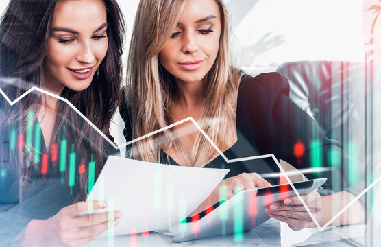 Two women reviewing documents and tablet with financial graphs overlay, modern office background, concept of data analysis and business strategy
