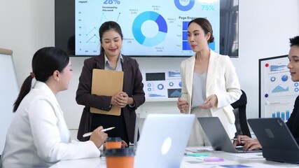 Professional businesswomen collaborating during strategic meeting, analyzing marketing performance data on large screen in modern conference room, showcasing leadership and teamwork - Powered by Adobe