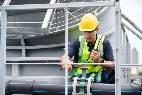 A worker talk on a walkie talkie and overseeing a cooling tower