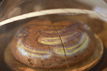 Delicious homemade marble bundt cake with chocolate and vanilla swirl patterns. An appetizing close up, distorted view through glass cover creates warm and comforting baking moment