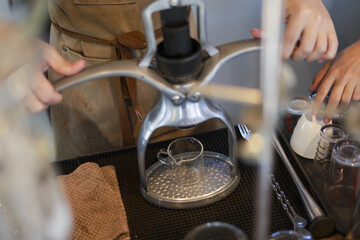 Focused barista making espresso coffee with manual press. close up of hand operated lever coffee machine in cafe, showing professional preparation of hot beverage