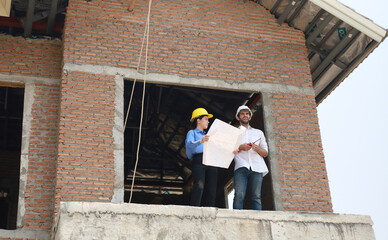 Architects and engineers work together to assess the progress of construction of houses in the...