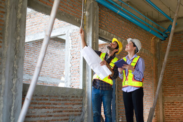 Male and female engineers discuss, inspect, and construct houses in the village. They are...