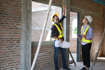 Male and female engineers discuss, inspect, and construct houses in the village. They are...