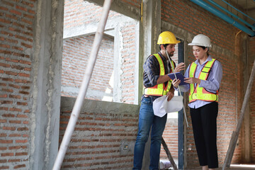 Male and female engineers discuss, inspect, and construct houses in the village. They are...