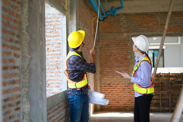 Male and female engineers discuss, inspect, and construct houses in the village. They are...