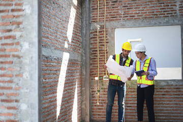 Male and female engineers discuss, inspect, and construct houses in the village. They are...