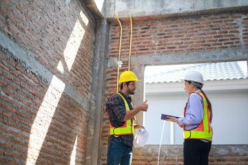 Male and female engineers discuss, inspect, and construct houses in the village. They are...