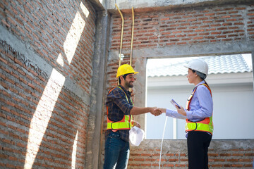 Male and female engineers discuss, inspect, and construct houses in the village. They are...