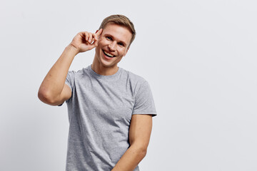 Smiling young man with short hair wearing casual gray t-shirt, looking cheerful while holding...