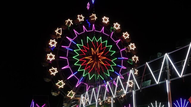 Ferris wheel with colorful neon lights in a fair or mela at night