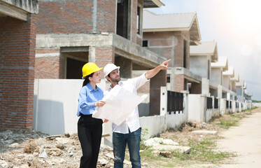 Female engineers and architects stand in front of a construction site, discussing their work, and discussing new technologies in housing construction.