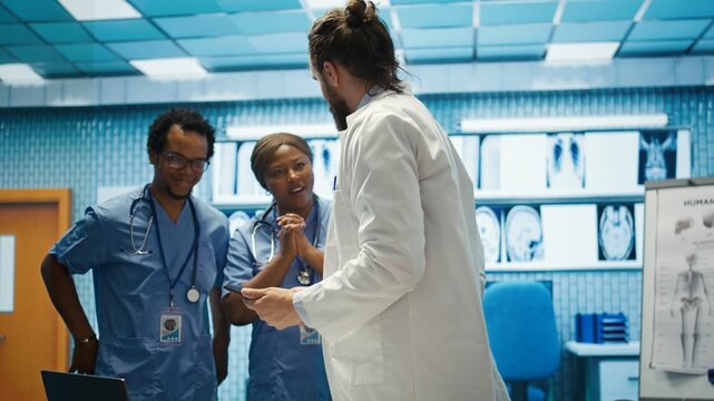 Cheerful confident doctors and nurses finding right treatment plan for a diagnosis, competent healthcare industry workers. Medical staff smiling and clapping hands, good news in a cabinet. Camera B.