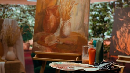 Empty artistic atelier with a rustic watercolor painting displayed on canvas, creative process with acrylic paint in a contemporary art and craft workshop. Masterpiece creation and supplies.