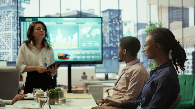 Diverse work team collaborating on project management tasks, utilizing smart technology and detailed analytics to optimize resource allocation and ensure enterprise objectives. Camera B.